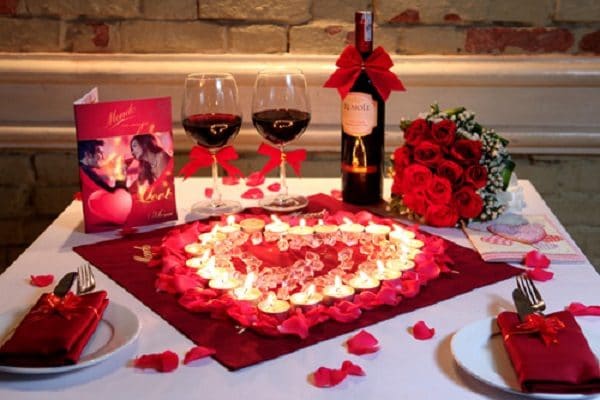 Bàn ăn với ánh nến và hoa hồng lãng mạn.